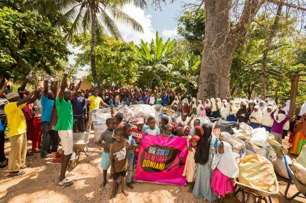 People & children cheering after cleanning and collecting garbage on a beach