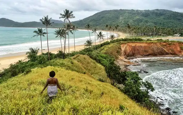 A woman in the middle of two different beach walking in the grass